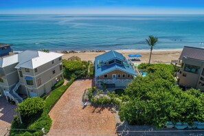 Una propiedad costera con camino de acceso pavimentado, piscina y vista a la playa.