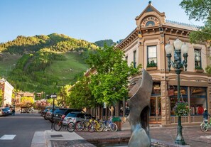 A historic building with a prominent entrance, a mountain backdrop, and a row of parked bicycles.