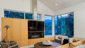 A modern living room with a fireplace, large windows, and a cozy seating area.