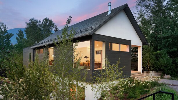 A modern house with a large glass window, a balcony, and a staircase leading to the entrance.