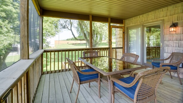 A covered outdoor deck with wicker furniture and a glass door leading to a backyard. - 2 Mi to Wineries: Calm Cottage on 90 Acres w/ Barn (Stewartstown)