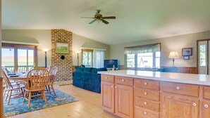 A spacious living area with a dining table, chairs, a sofa, and a kitchen with wooden cabinets. - 2 Mi to Wineries: Calm Cottage on 90 Acres w/ Barn (Stewartstown)
