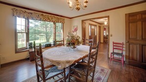 A dining room with a round table, wooden chairs, a chandelier, and a window with a floral valance. - Dayton Home w/ Pool & Deck on 37 Private Acres! (Dayton)