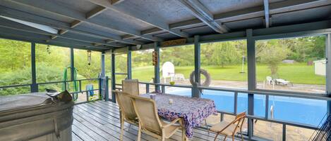 A covered outdoor area with a pool, wooden deck, and seating.