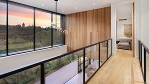 Un intérieur moderne avec une grande fenêtre offrant une vue panoramique, un mur en bois et une rambarde en verre.