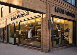 Ein Louis Vuitton Geschäft mit großen Schaufenstern, die Kleidung und Accessoires präsentieren.