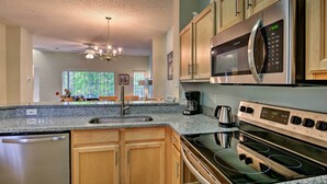 A modern kitchen with granite countertops, stainless steel appliances, wooden cabinets, and a built-in dishwasher. - 5 Mi to Disney: Emerald Island Resort Condo! (Kissimmee)