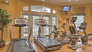 A gym with treadmills, elliptical machines, and a television screen. - 5 Mi to Disney: Emerald Island Resort Condo! (Kissimmee)
