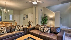 A living room with a brown leather sofa, a wooden coffee table, and a ceiling fan. - 5 Mi to Disney: Emerald Island Resort Condo! (Kissimmee)