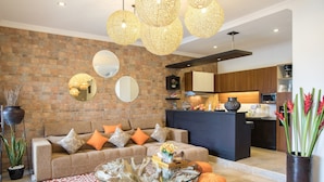 A living room with a sofa, coffee table, and decorative elements like a vase and mirror. - Zara The Bali Ocean View (Badung)