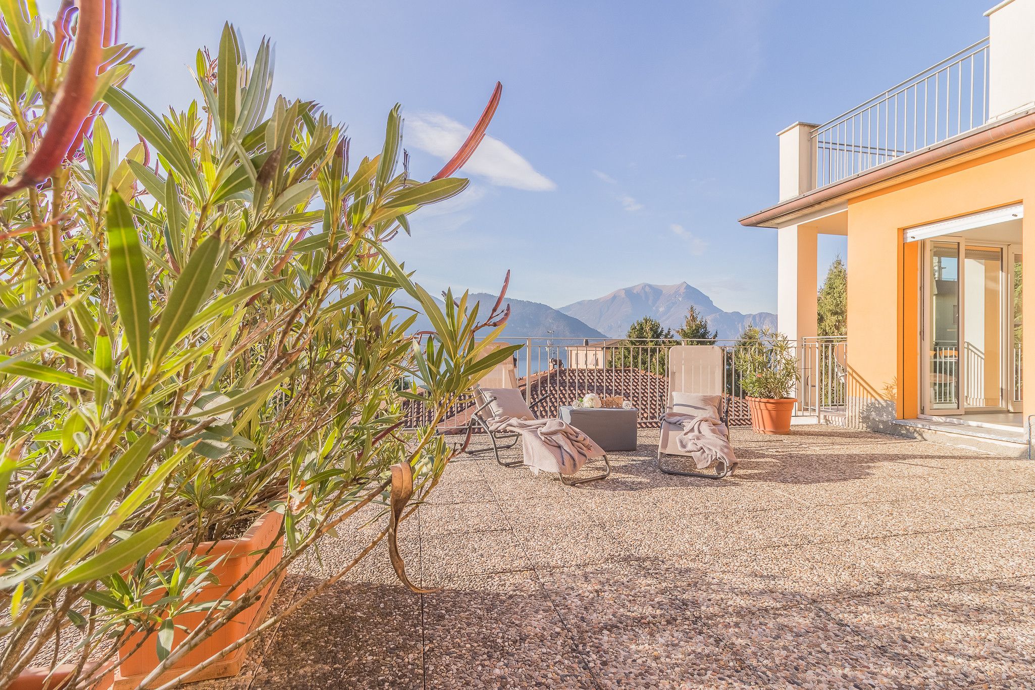 Un espace patio aménagé avec des meubles d’extérieur, des plantes en pot et une vue sur les montagnes.