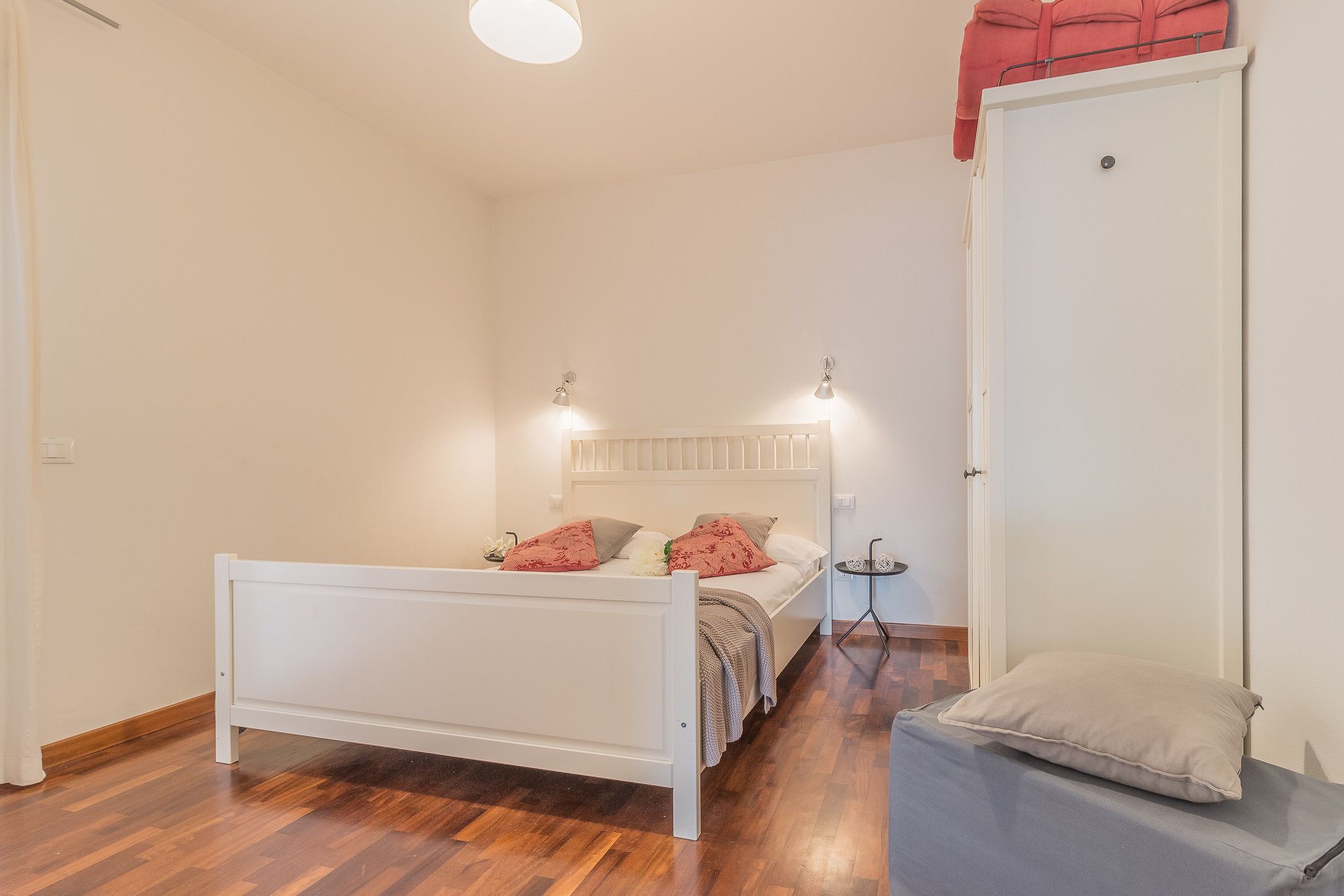 A bedroom with a bed, bedside table, and a wardrobe.