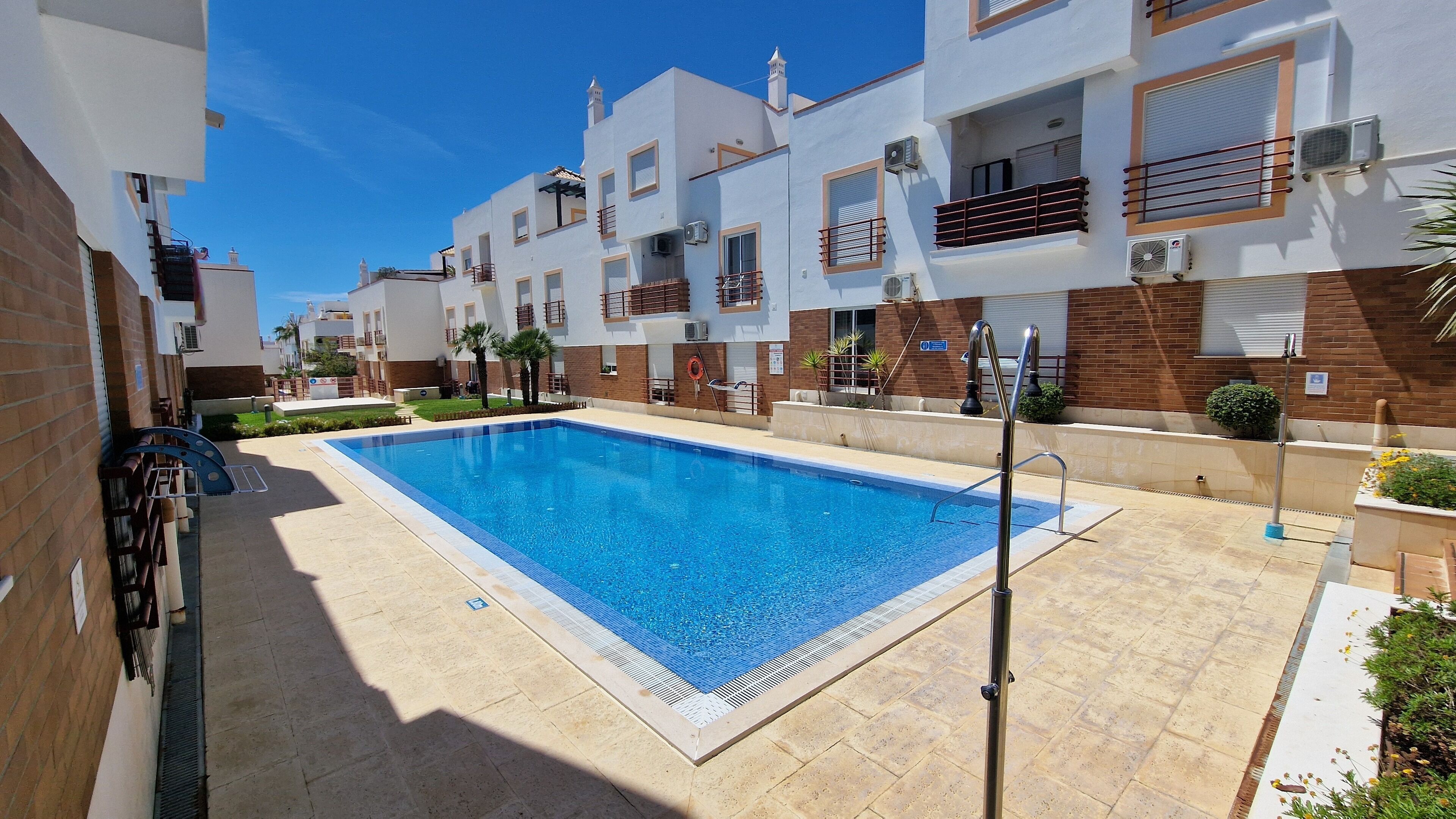 Piscina rodeada de edificios modernos con balcones y unidades de aire acondicionado.