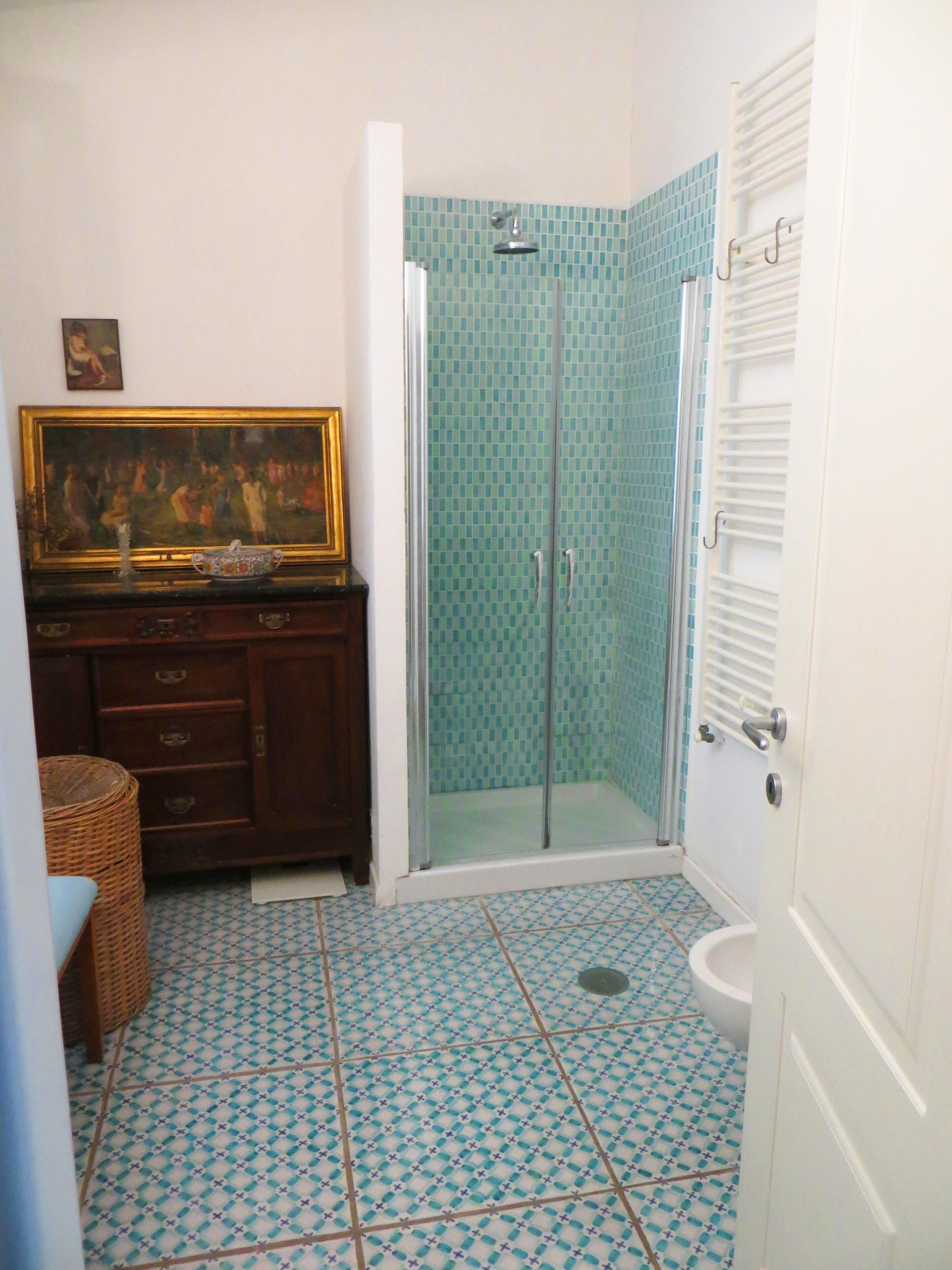 A bathroom with a shower, a toilet, and a vanity with drawers.