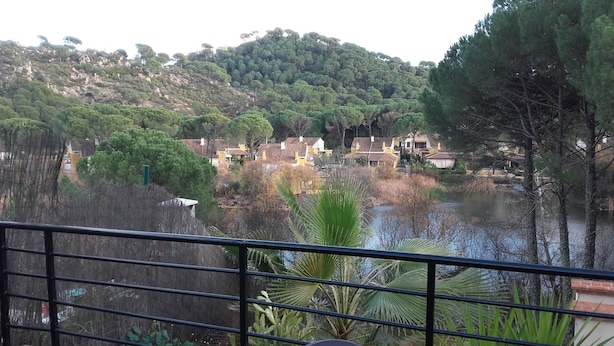 Vista de una zona residencial con casas en una colina, un cuerpo de agua y una barandilla al frente.