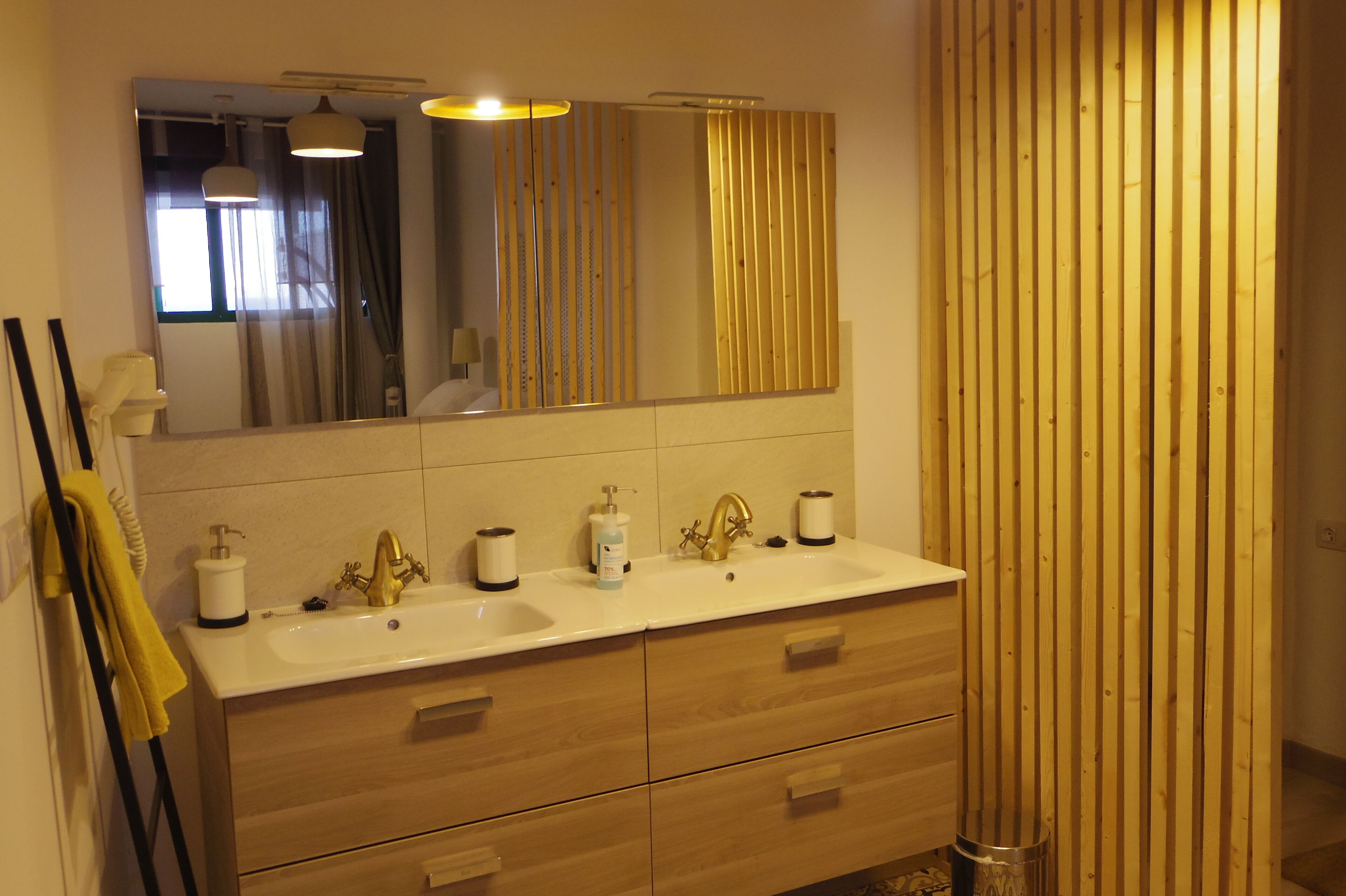 Ein modernes Badezimmer mit zwei Waschbecken, Holzschränken und einem großen Spiegel.