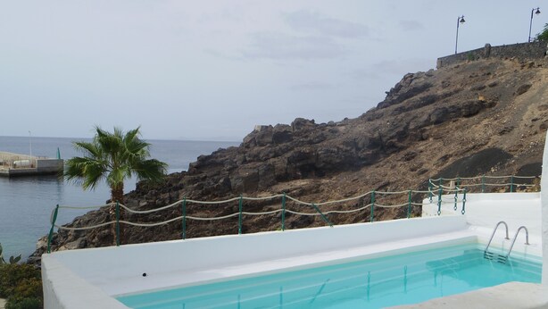 Una piscina con vistas despejadas al mar y terreno rocoso.
