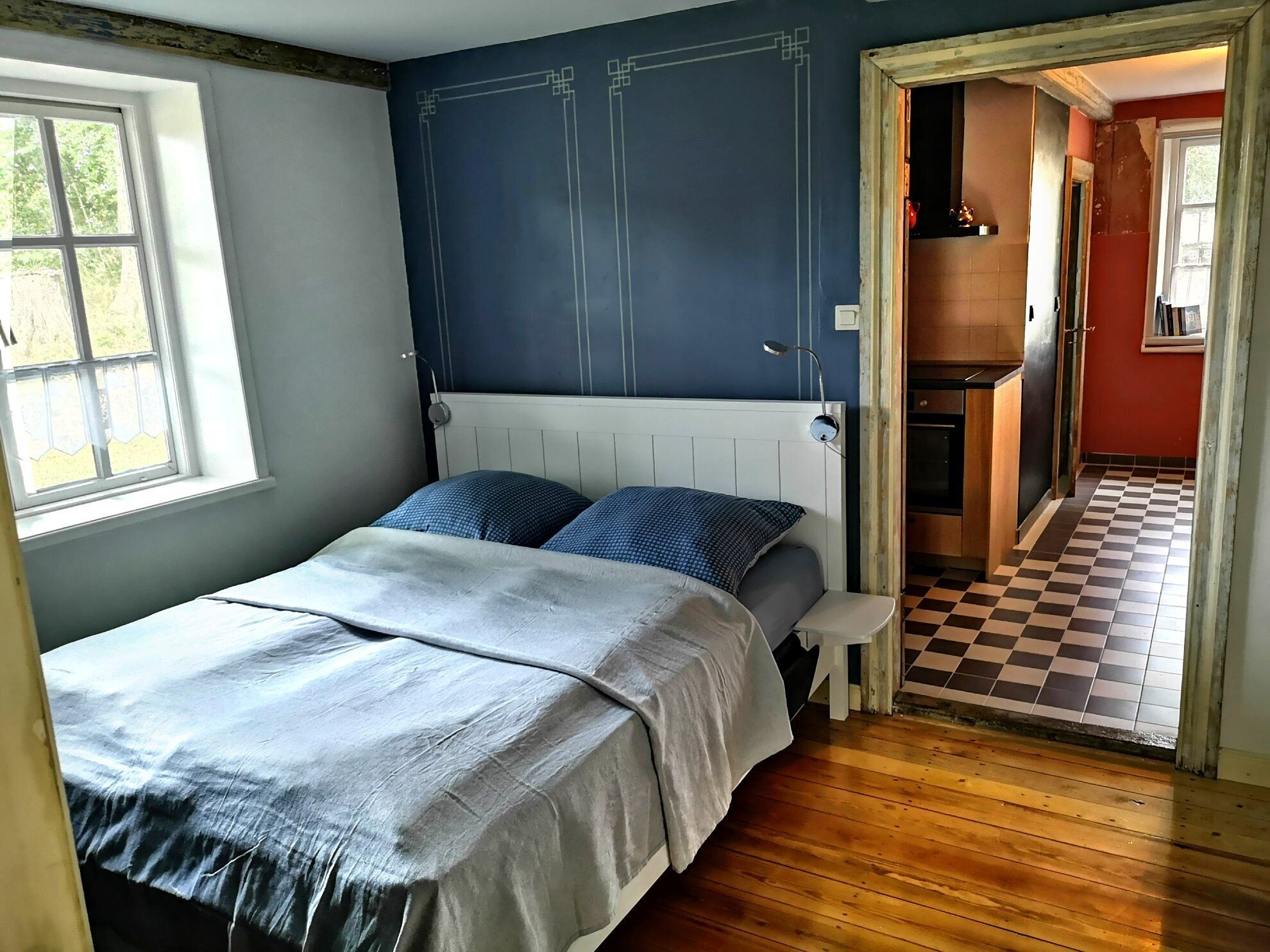 Une chambre à coucher avec un lit, une fenêtre et une vue sur la cuisine.