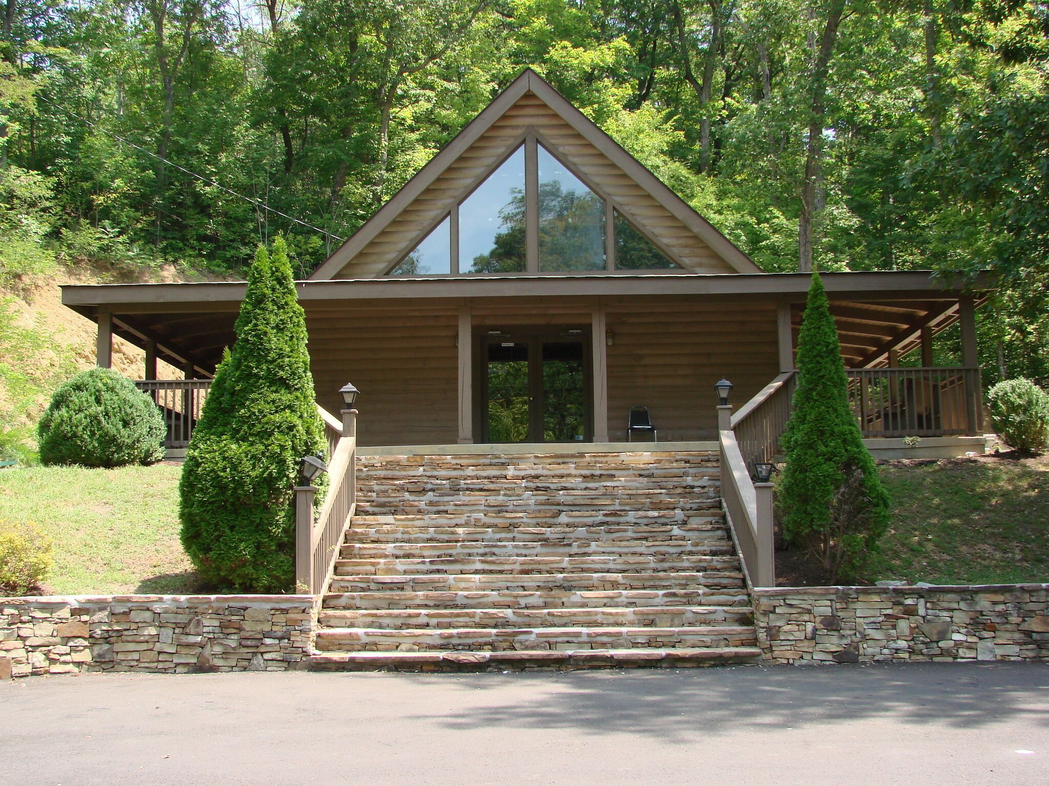 A lodge with a stone staircase leading to a wooden entrance, surrounded by trees.
