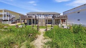 A beachfront property with a central building featuring a balcony, a covered patio, and a staircase leading to the upper floor. - Hazels Child Oceanfront Large  Beach House (North Myrtle Beach)