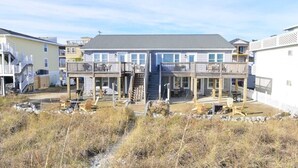 A two-story building with a central staircase, outdoor seating, and a beach view. - Hazels Child Oceanfront Large  Beach House (North Myrtle Beach)