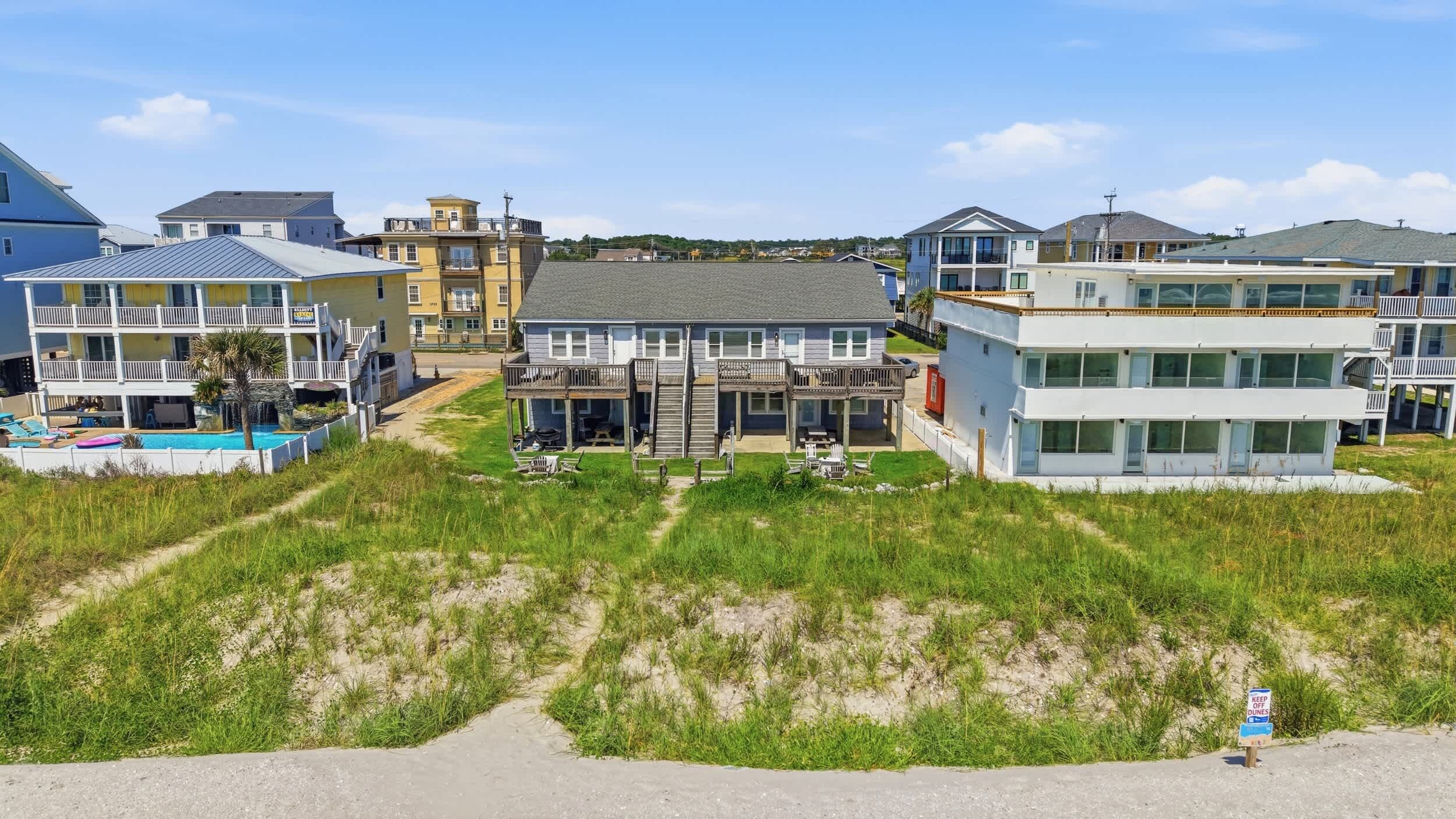 A coastal residential area with multiple two-story houses, a swimming pool, and a sandy beach.