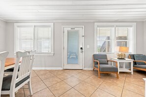 Une pièce comprenant une table à manger, des chaises, un canapé et une porte sur laquelle est apposé un panneau indiquant « Il est interdit de fumer ».