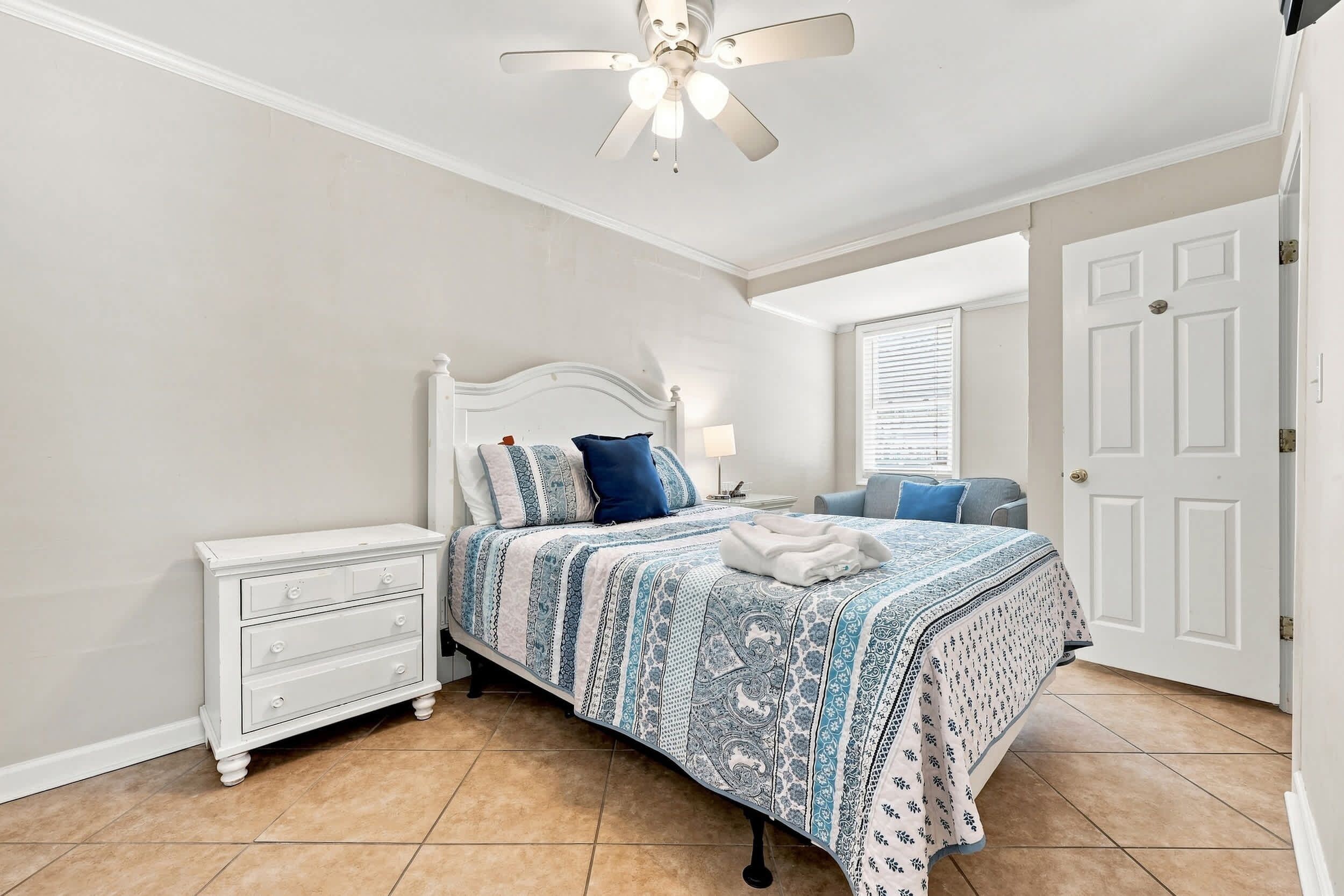 A bedroom with a bed, nightstand, dresser, and a ceiling fan.