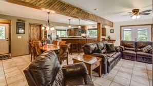 A spacious living area with leather sofas, a dining table, and a kitchen in the background.