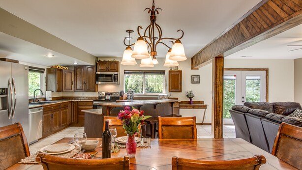 A spacious kitchen with wooden cabinets, a central island, and a dining area with a table set for four.