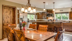 A spacious kitchen with wooden cabinets, a central island, and pendant lighting.