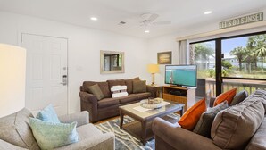 A living room with a sofa set, a coffee table, a TV, and a view of the outdoors.