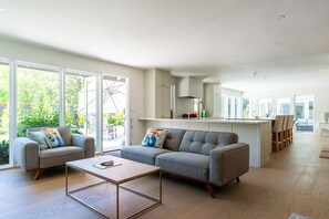 A modern living room with a sofa, coffee table, and a kitchen area with a dining set. - 4 BR California Living, Heated Pool 80F, Central AC, Pet, West Bellevue, 30d+ ok (Clyde Hill)
