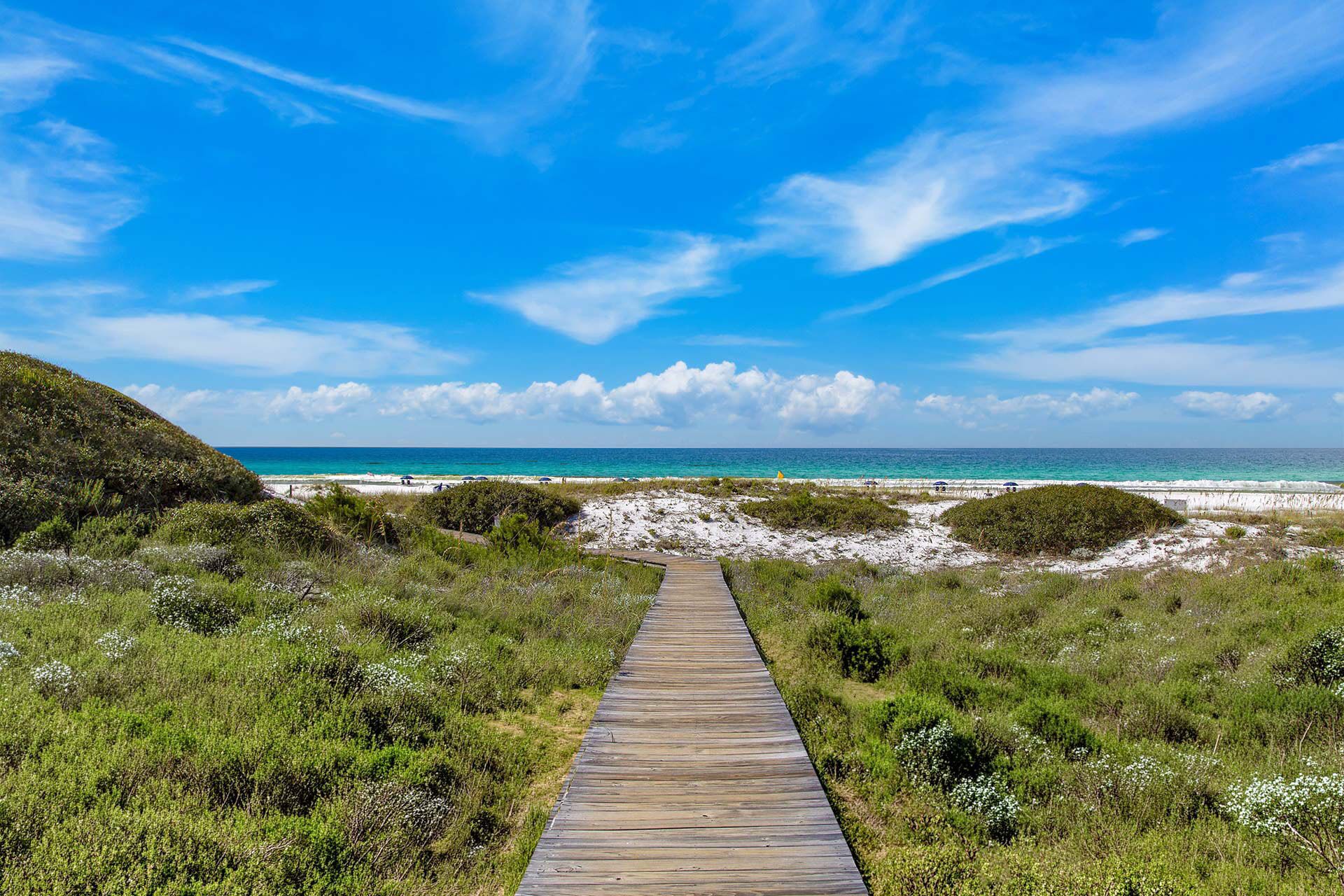 A wooden boardwalk leading to a beach with clear skies.