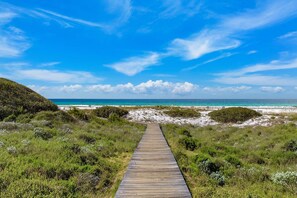 A wooden boardwalk leading to a beach with clear skies.