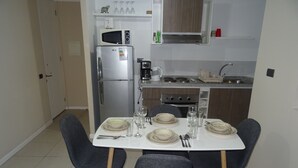 Een moderne keuken met een eettafel voor vier personen, voorzien van een koelkast, magnetron en fornuis.