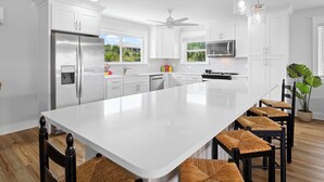 A modern kitchen with white cabinetry, a large island, and a ceiling fan. - Lone Star - Updated Gulf-View Home in Gulf Trace of Grayton Beach, Private Pool! (Gulf Trace)