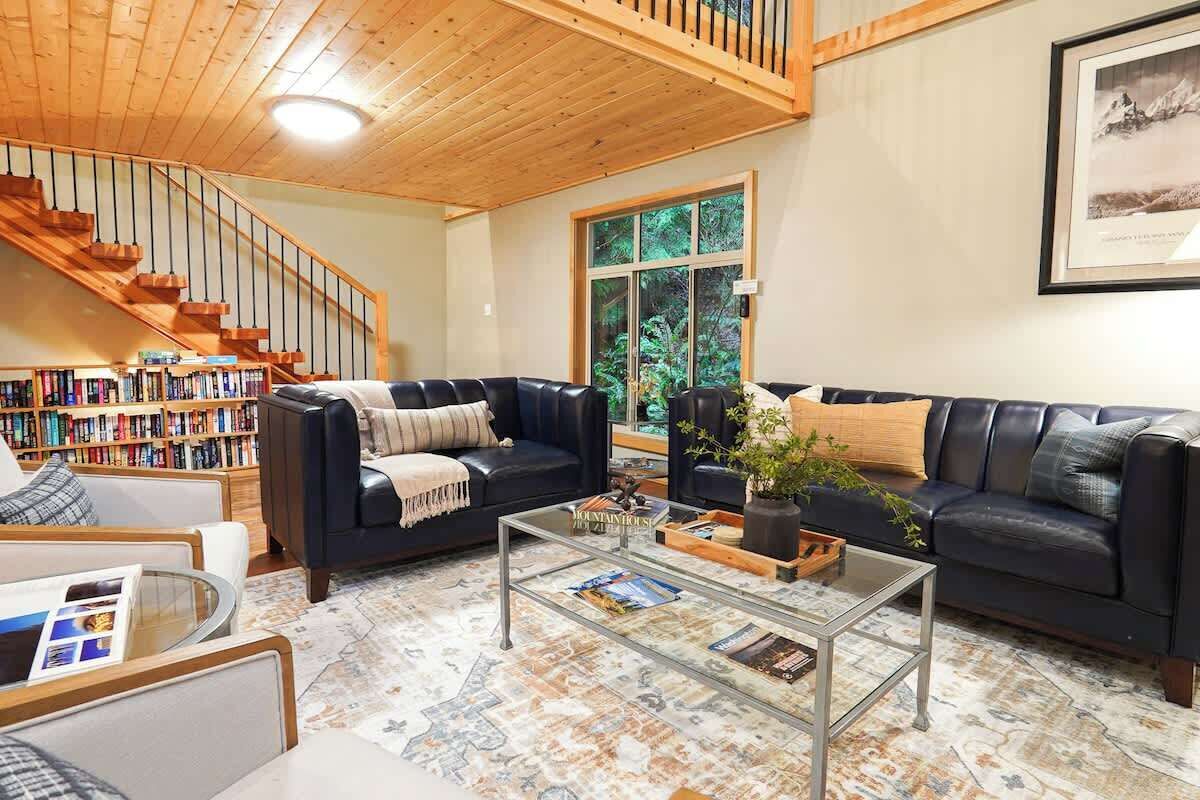 Un salon avec un escalier, des canapés en cuir, une table basse et une bibliothèque.