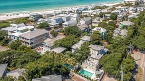 Ett bostadsområde vid kusten med hus, en strand och en swimmingpool.