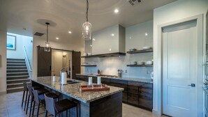 A modern kitchen with a large island, bar stools, and pendant lighting. - Steps to the Pool | Private Hot Tub | Red Rock Views | Arcadia #4 (Santa Clara)
