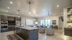A modern kitchen with dark wood cabinets, stainless steel appliances, and a large island. - Steps to the Pool | Private Hot Tub | Red Rock Views | Arcadia #4 (Santa Clara)