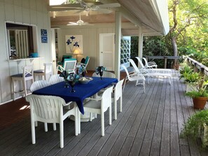 A covered outdoor dining area with white chairs and a table set with a blue tablecloth. - Mampoo Hill-- a Beachfront House 60 feet from the Ocean with optional Jeep (St. John)