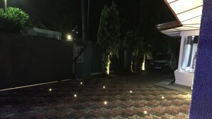A paved outdoor area with a patterned tile floor, a gated entrance, and a vehicle parked inside.