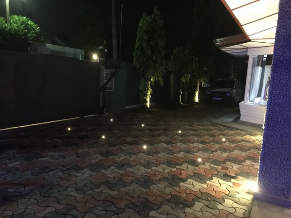 A paved outdoor area with a patterned tile floor, a gated entrance, and a vehicle parked inside.
