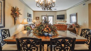 A dining area with a glass table surrounded by chairs, a chandelier, and a floral centerpiece. - Unit 2507 - FREE Attraction Ticket with EACH night Stay Including Dollywood (Pigeon Forge)