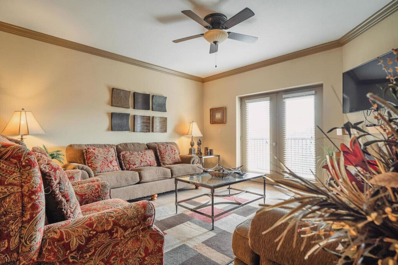 A living room with a sofa, armchairs, a coffee table, and a ceiling fan.