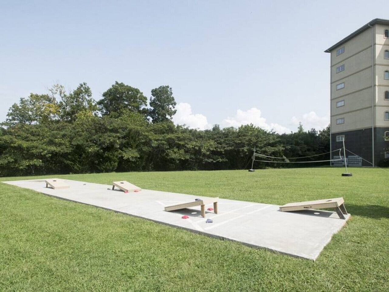 An outdoor area with a concrete surface, possibly for sports or activities, surrounded by grass and trees.