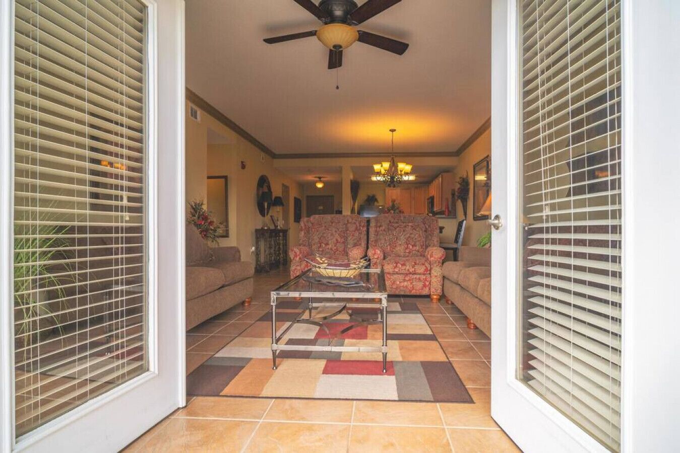 A living room with a sofa, armchairs, a coffee table, and a ceiling fan.