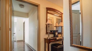 A hallway with a wooden floor, a desk with a lamp, a clock, and a mirror. - Unit 2507 - FREE Attraction Ticket with EACH night Stay Including Dollywood (Pigeon Forge)