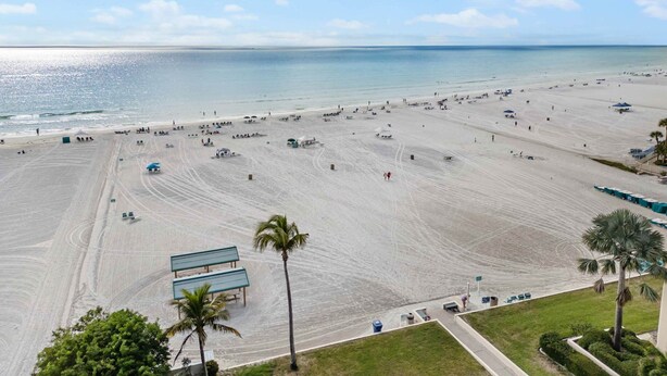 Ein weiter Strand mit blauem Himmel, Palmen und Blick auf den Ozean in der Ferne.